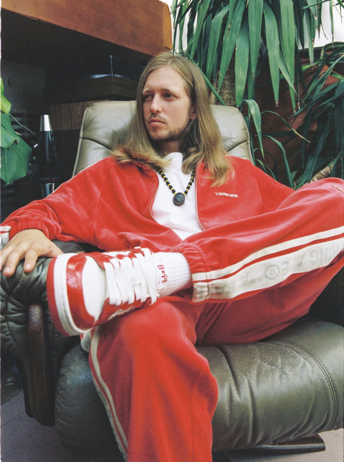 Busy Twist (Oliver Williams) sitting in a leather chair, film photograph